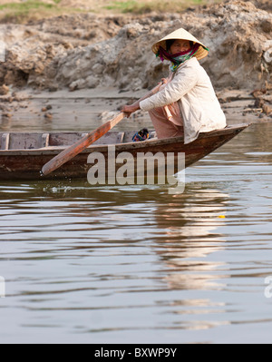 La donna in un tradizionale vietnamita hat remare una barca Foto Stock