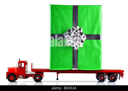 Un regalo presente di essere consegnato su un pianale camion. Isolato su uno sfondo bianco. Il carrello è un modello. Foto Stock