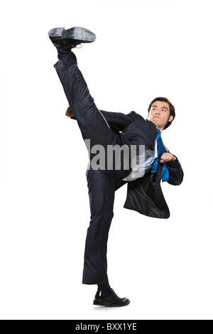 Imprenditore facendo un karate kick Foto Stock