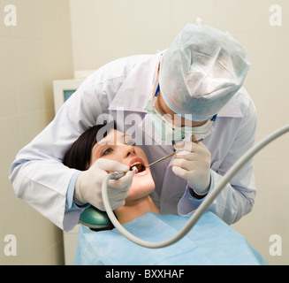 Foto di dentista in uniforme di esaminare la cavità orale del giovane paziente femmina Foto Stock