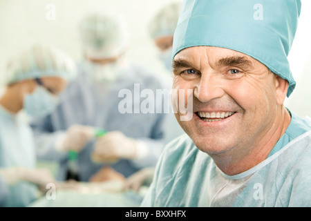 Ritratto di senior medico sorridente sullo sfondo dei suoi colleghi Foto Stock