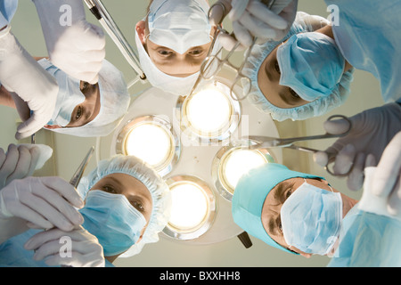 Vista dal di sotto di esperti chirurghi con strumenti medicali durante il funzionamento Foto Stock