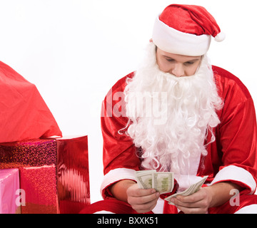 Foto di Santa seduto e conteggiare denaro con la pila di giftboxes nelle vicinanze Foto Stock