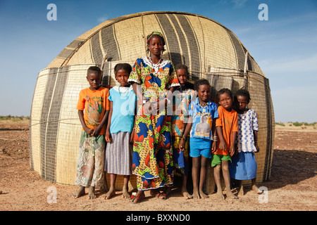 In Fulani villaggio di Jolooga nel nord del Burkina Faso, gli abitanti di un villaggio di stand al di fuori di una casa tradizionale fatta da stuoie di paglia. Foto Stock