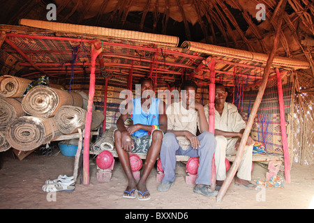 In Fulani villaggio di Jolooga nel nord del Burkina Faso, tre giovani uomini di sedersi su un letto tradizionale in una casa fatta di paglia. Foto Stock