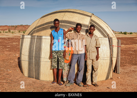 In Fulani villaggio di Jolooga nel nord del Burkina Faso, gli abitanti di un villaggio di stand al di fuori di una capanna tradizionale costituito da tessuto stuoia di paglia. Foto Stock