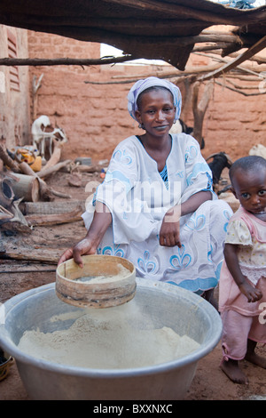 Una donna si prepara la farina di miglio per la cottura nella città di Djibo nel nord del Burkina Faso. Foto Stock