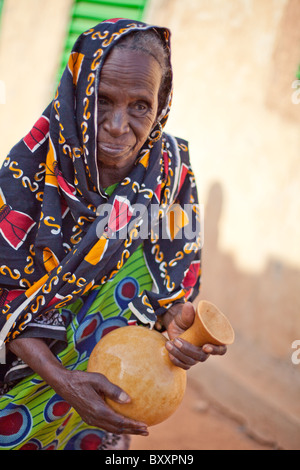 Un anziano Fulani donna nella città di Djibo nel nord del Burkina Faso scuote una zucca di latte fresco. Foto Stock