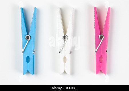 Tre in plastica colorata clothespins; sul bianco. Foto Stock