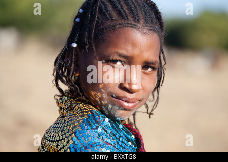 In un lavoro stagionale Fulani villaggio nel nord del Burkina Faso, riflessioni da paillettes di una giovane donna di scialle danza sul suo viso. Foto Stock