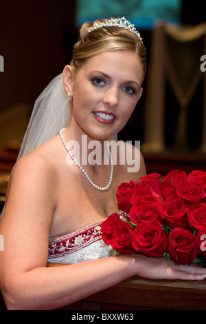 Sposa attraente con un mazzo di rose pone per le fotografie poco prima della cerimonia nuziale. Foto Stock