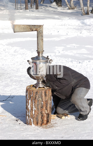 ULAN-UDE, Russia - 28 febbraio: un uomo suscita un classico vecchio samovar l'ultimo giorno del festival di pancake, quando la gente mangia pancake Foto Stock