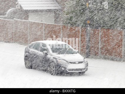 Guidare l'auto lungo la superficie stradale residenziale non trattata nella neve Blizzard Brentwood Essex Inghilterra Regno Unito Foto Stock