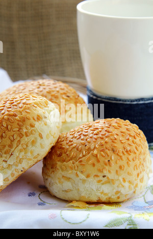 Panini freschi con semi di sesamo e un bicchiere di latte prima colazione Foto Stock