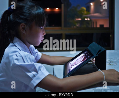 IPad bambino. Ragazza tailandese giovane che usa un iPad a casa. Thailandia S. E. Asia Foto Stock