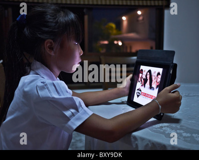 IPad bambino. Ragazza tailandese giovane che usa un iPad a casa. Thailandia S. E. Asia Foto Stock