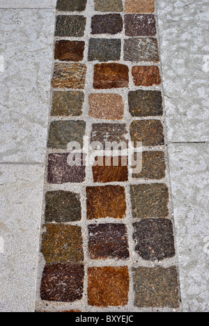 Pavimentazione in lastre e blocchi di porfido con bianco e sfumature colorate Foto Stock