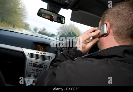 Maschio utilizzando il telefono cellulare durante la guida di auto Foto Stock