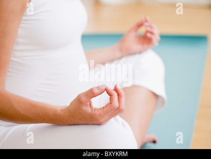 Giovane donna incinta meditando Foto Stock