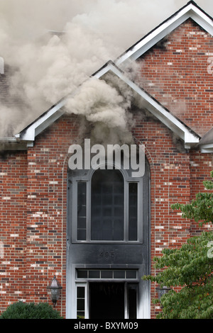 Pennacchi di fumo dalla porta di una casa come il fuoco combattente per la battaglia per mettere fuori casa di fuoco di Charlottesville, Virginia. Foto Stock