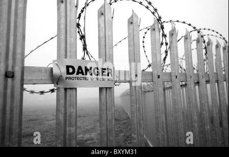 Segnaletica di pericolo attenzione della concertina filo spinato montato su acciaio zincato recinzione appuntita. Foto Stock