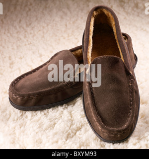 Una coppia di mens brown pantofole scarpe su una pelle di pecora sfondo vello Foto Stock