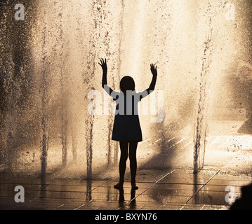 Silhouette della ragazza che gioca nella fontana Foto Stock