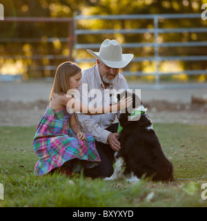 Ragazza di accarezzare il cane con il nonno Foto Stock