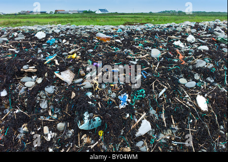 Detritis in plastica e detriti cucciolata le rocce su una spiaggia, County Clare, costa Ovest dell Irlanda Foto Stock