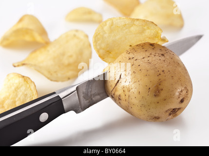 Immagine concettuale - il coltello taglia patate fresche e potato chips sono ottenuti. Foto Stock