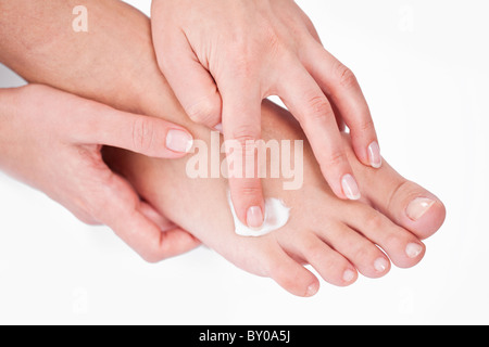 Giovane donna si applica la crema sul suo morchie. Su uno sfondo bianco. Foto Stock