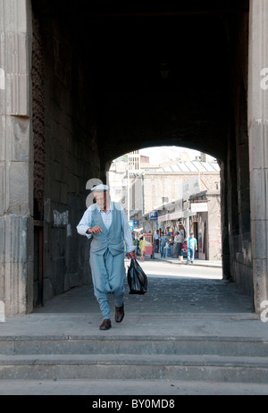 Un curdo cammina attraverso la porta Mardin all'estremità meridionale delle mura della città vecchia di Diyarbakir in Turchia. Foto Stock