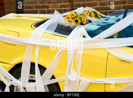 Nastri di carta festone un giallo Alfa Romeo Auto convertibile con girasoli nel sedile posteriore in corrispondenza di un matrimonio italiano Foto Stock