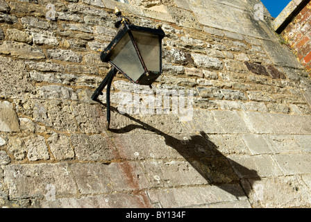 Un ombra lunga di questa lanterna vittoriano appeso a una parete di pietra Foto Stock