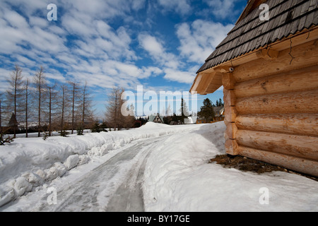 Tradizionale baita polacca a Zakopane durante la stagione invernale con la strada sterrata in primo piano Foto Stock