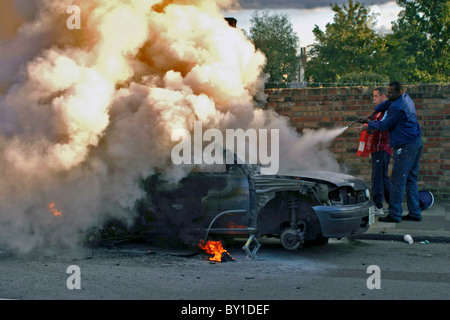 Due persone che cercano di estinguere un incendio per auto Foto Stock