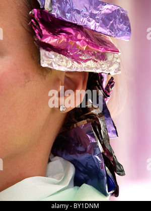 Closeup colpo di donna con rosa viola alluminio foglio di stagno nei suoi capelli che è utilizzato quando la colorazione dei capelli. Foto Stock