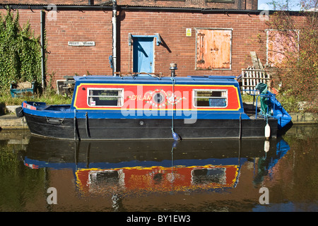 'Dylan' - barca ormeggiata accanto a locali industriali su Ashton Canal, Ashton Under Lyne, Tameside, Greater Manchester, Inghilterra, Regno Unito Foto Stock