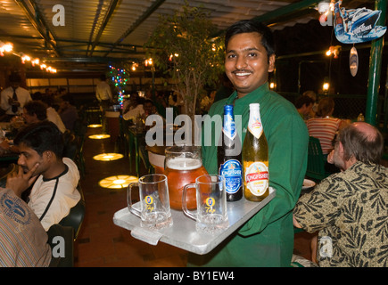 Un cameriere che serve Kingfisher birra chiara in un bar ristorante in India Foto Stock