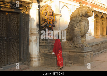 Donna indù che offre a un santuario in antica Bhaktapur vicino a Kathmandu, Nepal Foto Stock