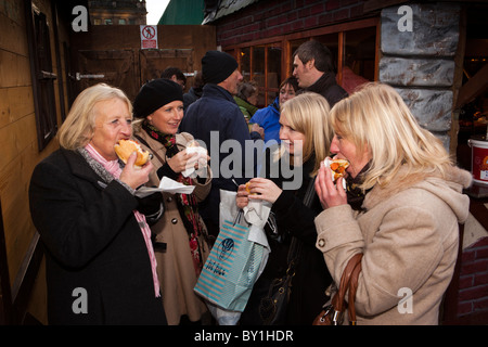 Regno Unito, Inghilterra, nello Yorkshire, Leeds, Milennium Square, Christkindelmarkt, gruppo di donne mangiare spuntini Foto Stock