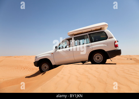 In Oman Wahiba Sands. Un 4x4 facilita su una duna di sabbia nel sole di mezzogiorno. Foto Stock