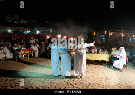 Gli uomini frequentano beduino tradizionale celebrazione dei matrimoni danza professionale con una danzatrice del ventre da Beirut come lei intrattiene gli ospiti. Foto Stock