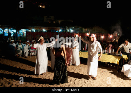 Gli uomini frequentano beduino tradizionale celebrazione dei matrimoni danza professionale con una danzatrice del ventre da Beirut come lei intrattiene gli ospiti. Foto Stock