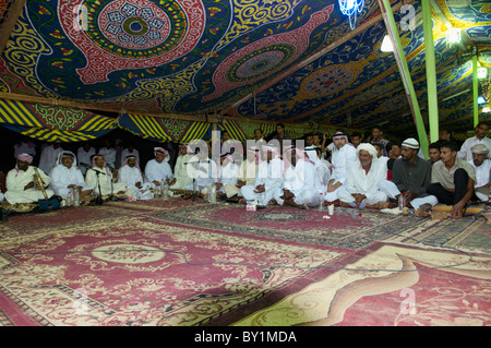 Ospiti seduti attendono intrattenimento durante un beduino tradizionale celebrazione di matrimonio. El Tur, Sinai, Egitto Foto Stock