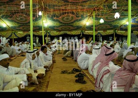 Ospiti seduti attendono intrattenimento durante un beduino tradizionale celebrazione di matrimonio. El Tur, Sinai, Egitto Foto Stock