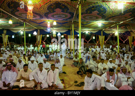 Ospiti seduti attendono intrattenimento durante un beduino tradizionale celebrazione di matrimonio. El Tur, Sinai, Egitto Foto Stock