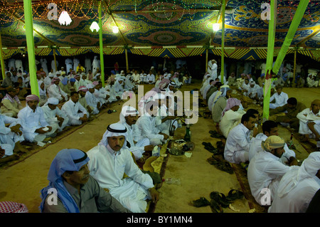 Ospiti seduti attendono intrattenimento durante un beduino tradizionale celebrazione di matrimonio. El Tur, Sinai, Egitto Foto Stock