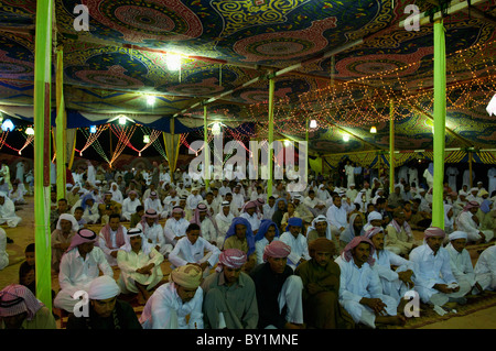 Ospiti seduti attendono intrattenimento durante un beduino tradizionale celebrazione di matrimonio. El Tur, Sinai, Egitto Foto Stock