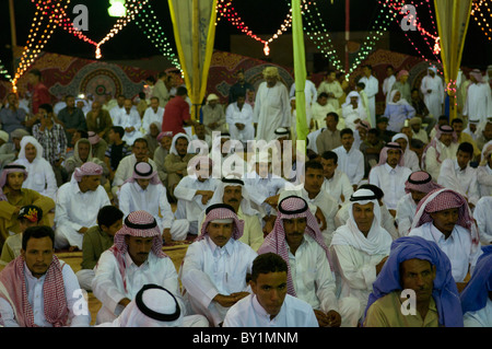 Ospiti seduti attendono intrattenimento durante un beduino tradizionale celebrazione di matrimonio. El Tur, Sinai, Egitto Foto Stock